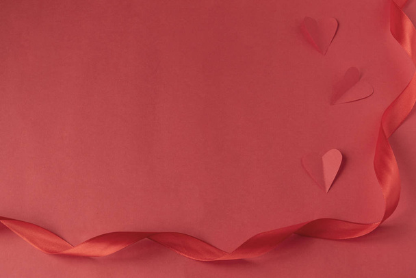 Κόκκινη σατέν κορδέλα σε κόκκινο φόντο και καρδιά. Ημέρα του Αγίου Βαλεντίνου για την ημέρα του Αγίου Βαλεντίνου. Αγάπη - Φωτογραφία, εικόνα