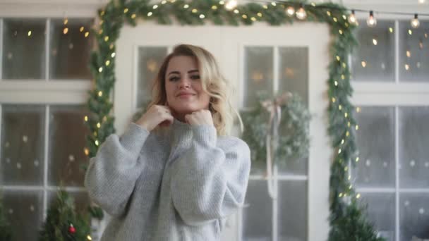 Európai vonzó nő meleg ruhában pulóverbe öltözik, és a kamerába néz, skandináv téli belső tér, hangulatos új év otthoni légkör, Full Hd 120fps Prores Hq - Felvétel, videó