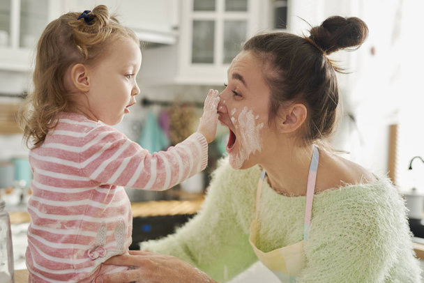 Mama i jej córeczka bawią się mąką w kuchni  - Zdjęcie, obraz