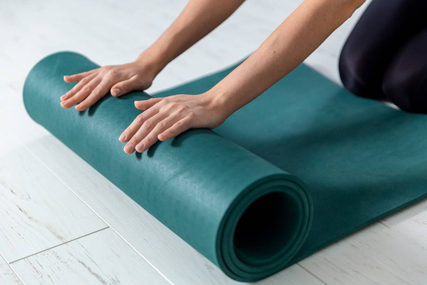 Close-up foto van yoga groene mat. Vrouw bereidt zich voor op indoor oefeningen. - Foto, afbeelding