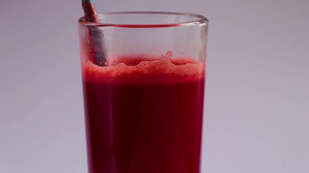 πίνετε φρέσκο καρότο και χυμό παντζαριού σε γυάλινο ποτήρι σε λευκό φόντο - Πλάνα, βίντεο
