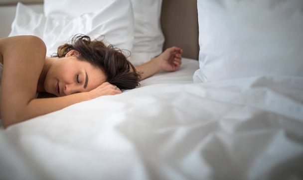 ベッドで寝てる美しい若い女性  - 写真・画像