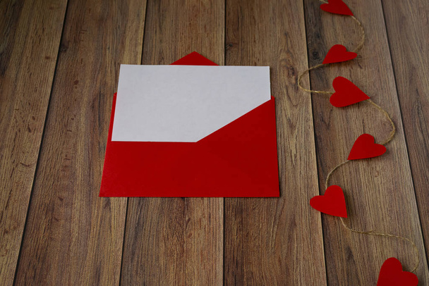 Tło na Walentynki. Girlanda serc, czerwona koperta na drewnianym tle. Walentynki - Zdjęcie, obraz