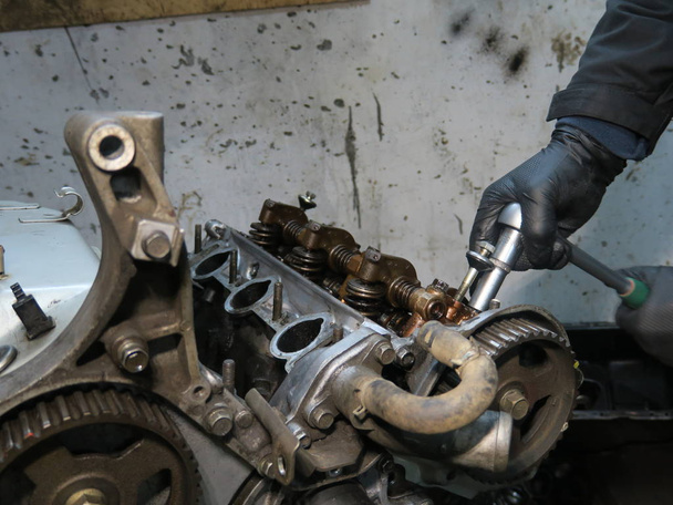 La barra de conexión, el pistón y el bloque del cilindro en una condición desmontada. Hombre s mano fijación de un motor
 - Foto, imagen