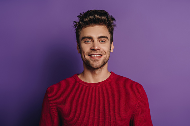 young, handsome man smiling at camera on purple background - Foto, imagen