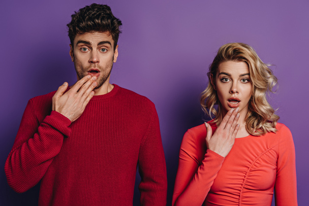 shocked man and woman looking at camera on purple background - Foto, immagini
