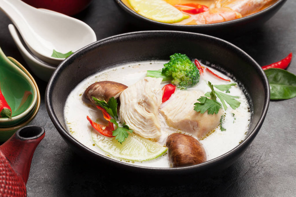 Tom Yum e Tom Kha tradicionais sopas tailandesas com frutos do mar, frango, cogumelos, leite de coco e especiarias quentes. Com panela de chá verde e tigela
 - Foto, Imagem