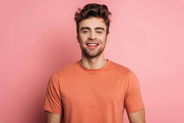 handsome, happy man smiling at camera on pink background - Photo, Image