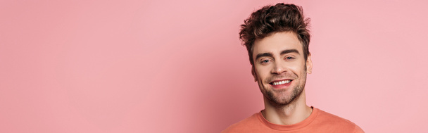 panoramic shot of happy young man smiling at camera on pink background - Fotoğraf, Görsel