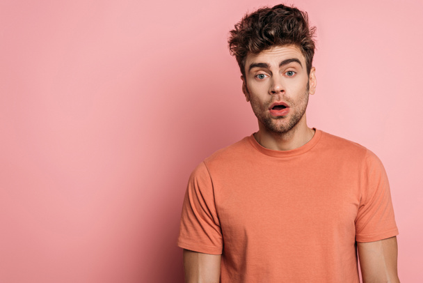 discouraged young man looking at camera on pink background - Fotografie, Obrázek
