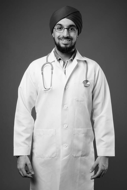 Estudio de joven barbudo indio Sikh hombre médico sobre fondo gris en blanco y negro - Foto, imagen