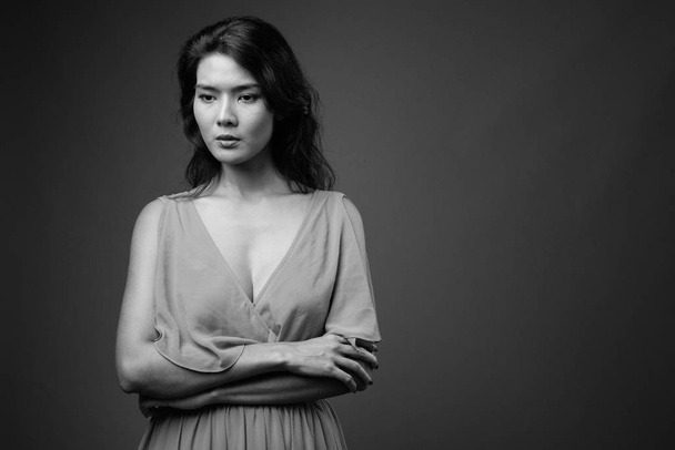 Studio colpo di bella donna asiatica che indossa abito contro sfondo grigio in bianco e nero - Foto, immagini
