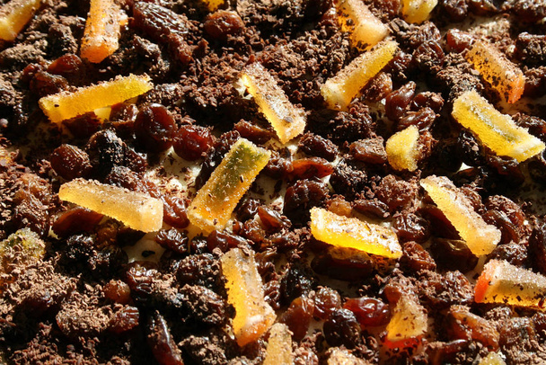 Raisins and candied orange slices coated with grated chocolate. Decorated surface of tasty sweet cake close-up background. Homemade sweets - Photo, Image