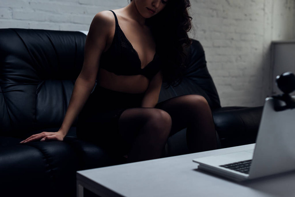 Vista ritagliata di sensuale giovane donna in lingerie in posa presso la fotocamera web sul divano
 - Foto, immagini