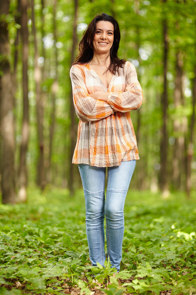 Beautiful woman with arms folded in a forest - Foto, imagen