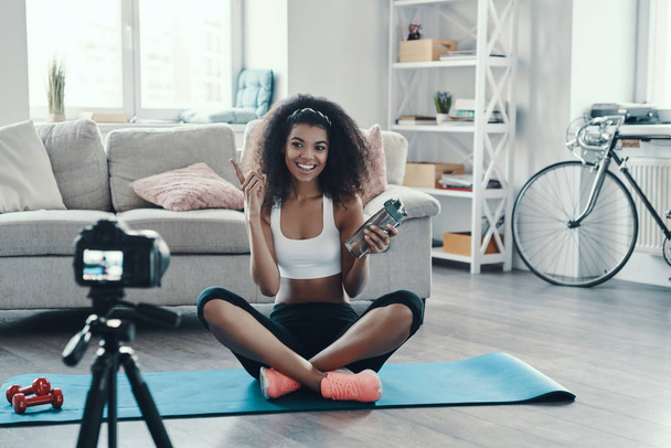 Fit young African woman working out and smiling while making social media video - Foto, Imagem