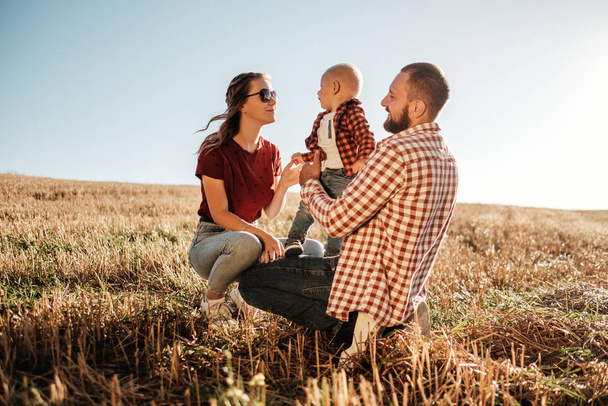 Happy Young Family Mom and Dad with Their Little Son Enjoying Summer Weekend Picnic Outside the City in the Field at Sunny Day Sunset, Vacation Time Concept - Fotoğraf, Görsel