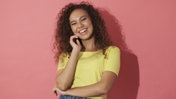 Cheerful pretty curly woman laughing and looking at the camera over pink background - Séquence, vidéo