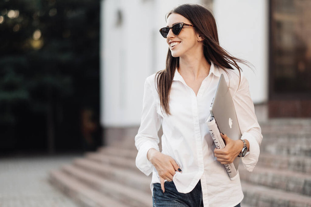 TERNOPIL, UKRAINE - 28 AOÛT 2019 : Portrait d'une fille à la mode vêtue d'un jean et d'une chemise blanche tenant un ordinateur portable Apple Macbook Air, Travailleur indépendant, Femme d'affaires, Femme Power Concept
 - Photo, image