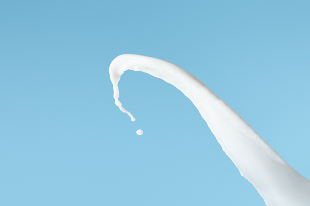 friss fehér tej fröccsenés izolált kék - Fotó, kép