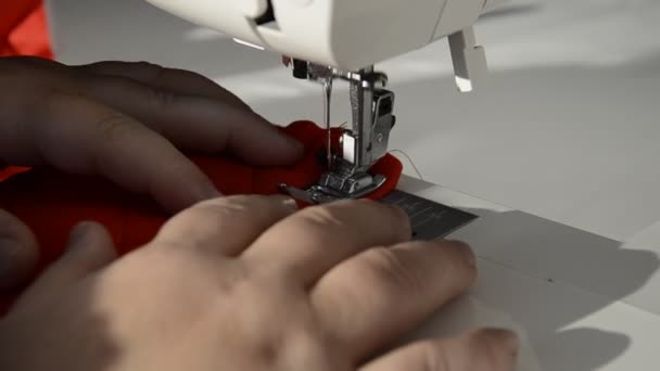 La máquina de coser está llena de hilo de coser rojo y tela roja.
.  - Metraje, vídeo