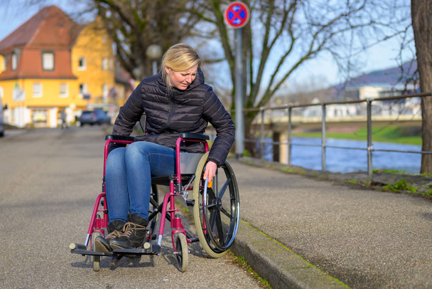 Femme handicapée manoeuvrant son fauteuil roulant
 - Photo, image