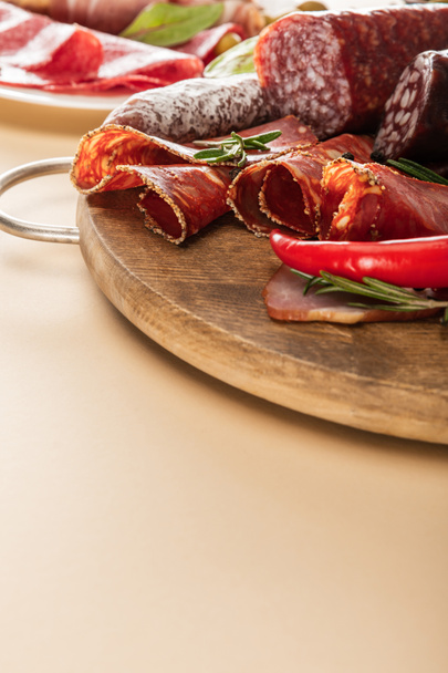 delicious meat platters served with rosemary and chili pepper on wooden board on beige background - Photo, Image