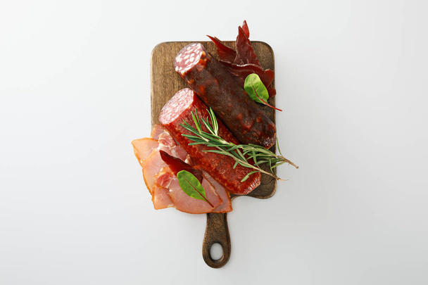 vista superior de deliciosa bandeja de carne servida con romero sobre tabla de madera aislada en blanco
 - Foto, Imagen