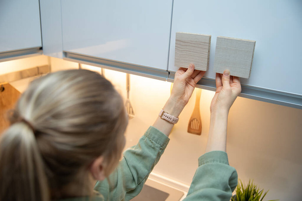 Frau wählt Materialien für Küchenschränke aus Laminatmustern - Foto, Bild