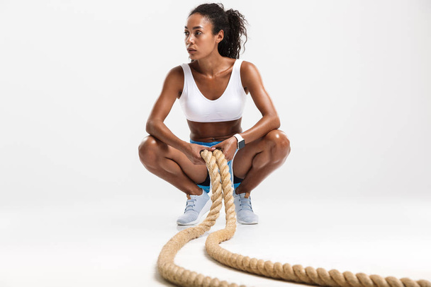 Portrait of african american woman doing exercises with batting ropes - Fotoğraf, Görsel
