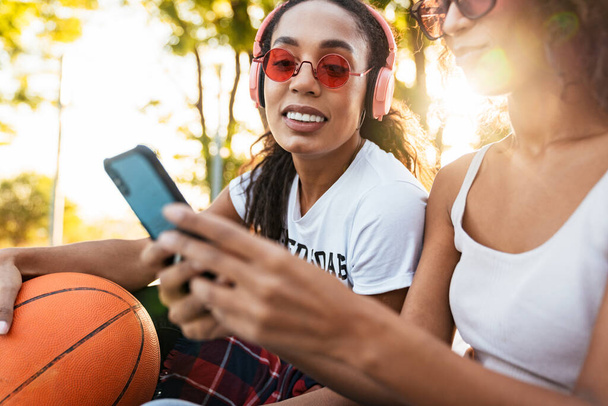Image of american girls sitting on playdround with basketball an - Fotografie, Obrázek