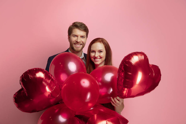Valentines day celebration, happy caucasian couple isolated on coral background - Foto, afbeelding