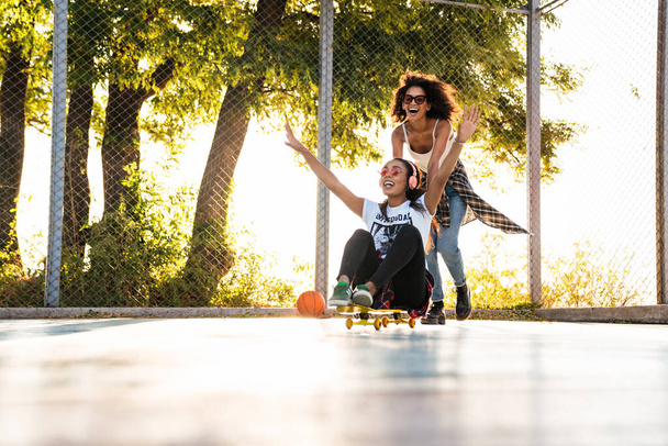 Image of american girls having fun and riding skateboard on play - Photo, image