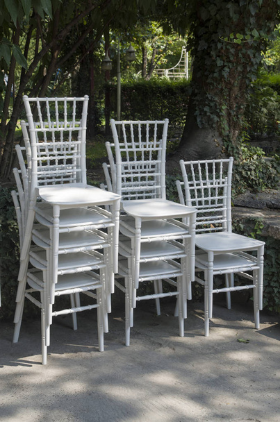 Exquisite wooden white chairs one on the other in garden - Photo, Image