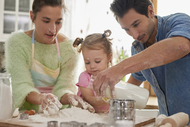 Klein meisje maakt koekjes met ouders - Foto, afbeelding