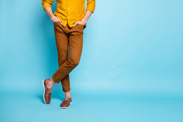 Cropped photo of confident man legs in footwear crossed with hands in pockets standing confidently isolated over pastel color background - Foto, Imagem