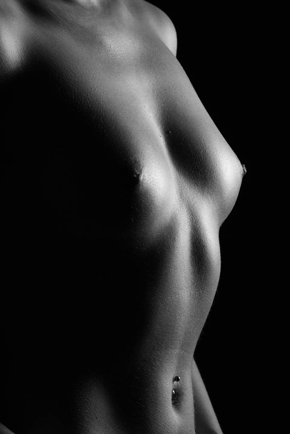 low key shot of a standing woman,visible chest and abdomen,shot in black and white - Photo, Image