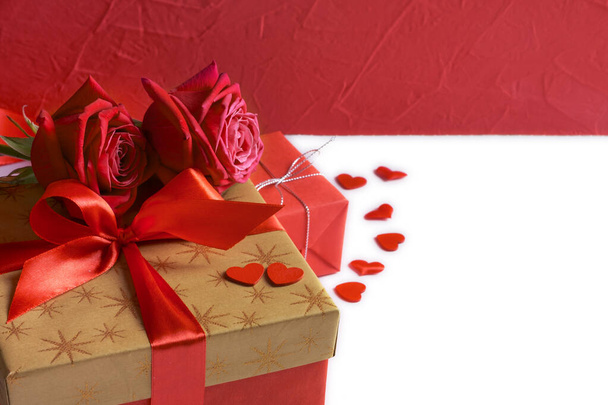 Caixa de presente dourada com fita vermelha, rosas e pequenos corações isolados no branco, conceito do dia dos namorados
 - Foto, Imagem