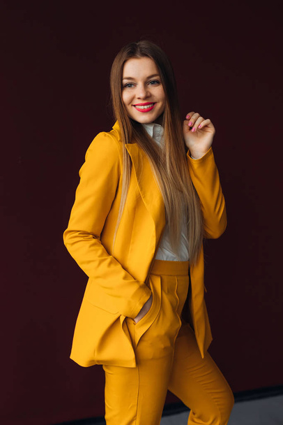 Elegantes Mädchen posiert in einem gelben Anzug. Schönes Lächeln. Studio. - Foto, Bild