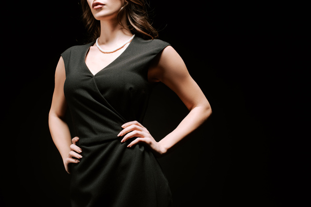 обрізаний вид впевненої жінки, що стоїть руками на стегнах ізольовано на чорному
  - Фото, зображення