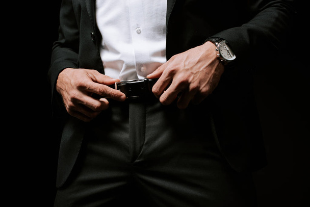 cropped view of man touching belt isolated on black  - 写真・画像