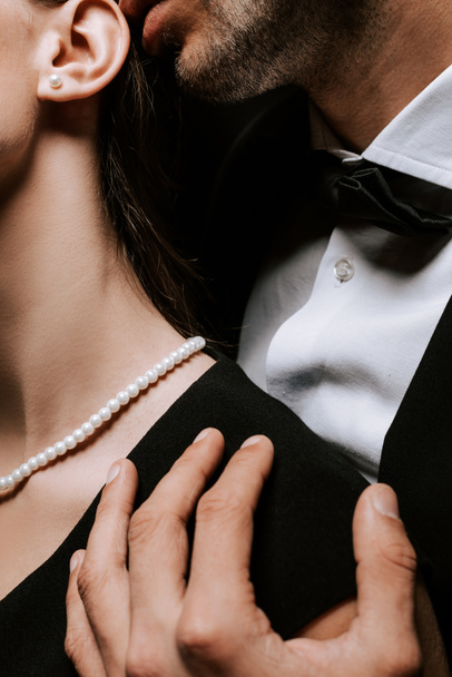oříznutý pohled na muže dotýkající se ženy s perleťovým náhrdelníkem na krku  - Fotografie, Obrázek