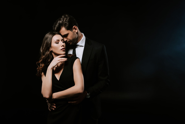 sensual man standing with attractive woman in dress on black  - Photo, Image