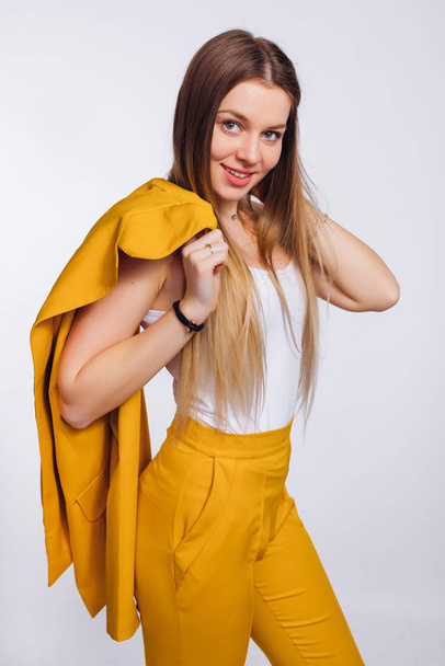 girl with a long hair holds a yellow jacket on her shoulder. yel - Photo, Image
