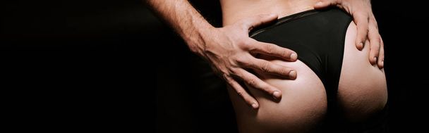 panoramic shot of of man touching buttocks of sexy woman isolated on black  - Fotoğraf, Görsel