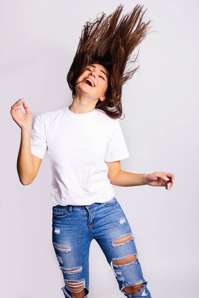 girl having fun and waving her hair in studio. stylish jeans and - Zdjęcie, obraz