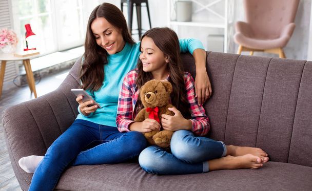 Mother and her daughter sitting on sofa  - Photo, Image