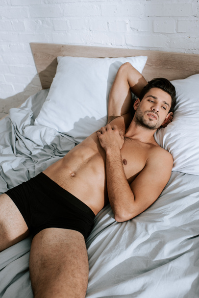 sunlight on shirtless man resting on bed at home  - Foto, Imagen