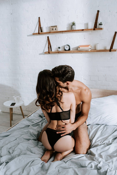 back view of seductive girl sitting on shirtless man in bedroom  - Φωτογραφία, εικόνα
