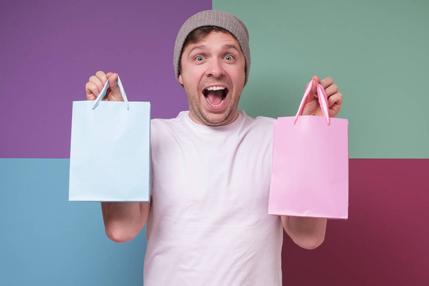 Позитивный мужчина с двумя голубыми и розовыми пакетами в подарок для ребенка
. - Фото, изображение